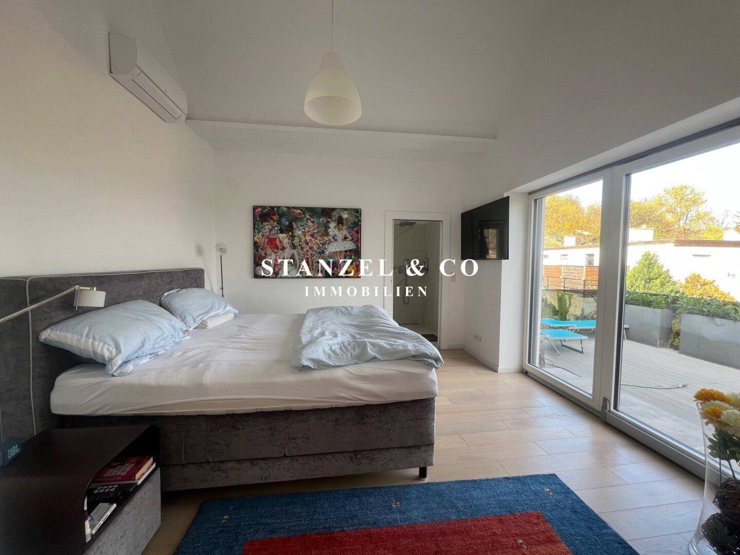 Helles Schlafzimmer mit Einbauschränken, Holzboden und Zugang zur Terrasse.
