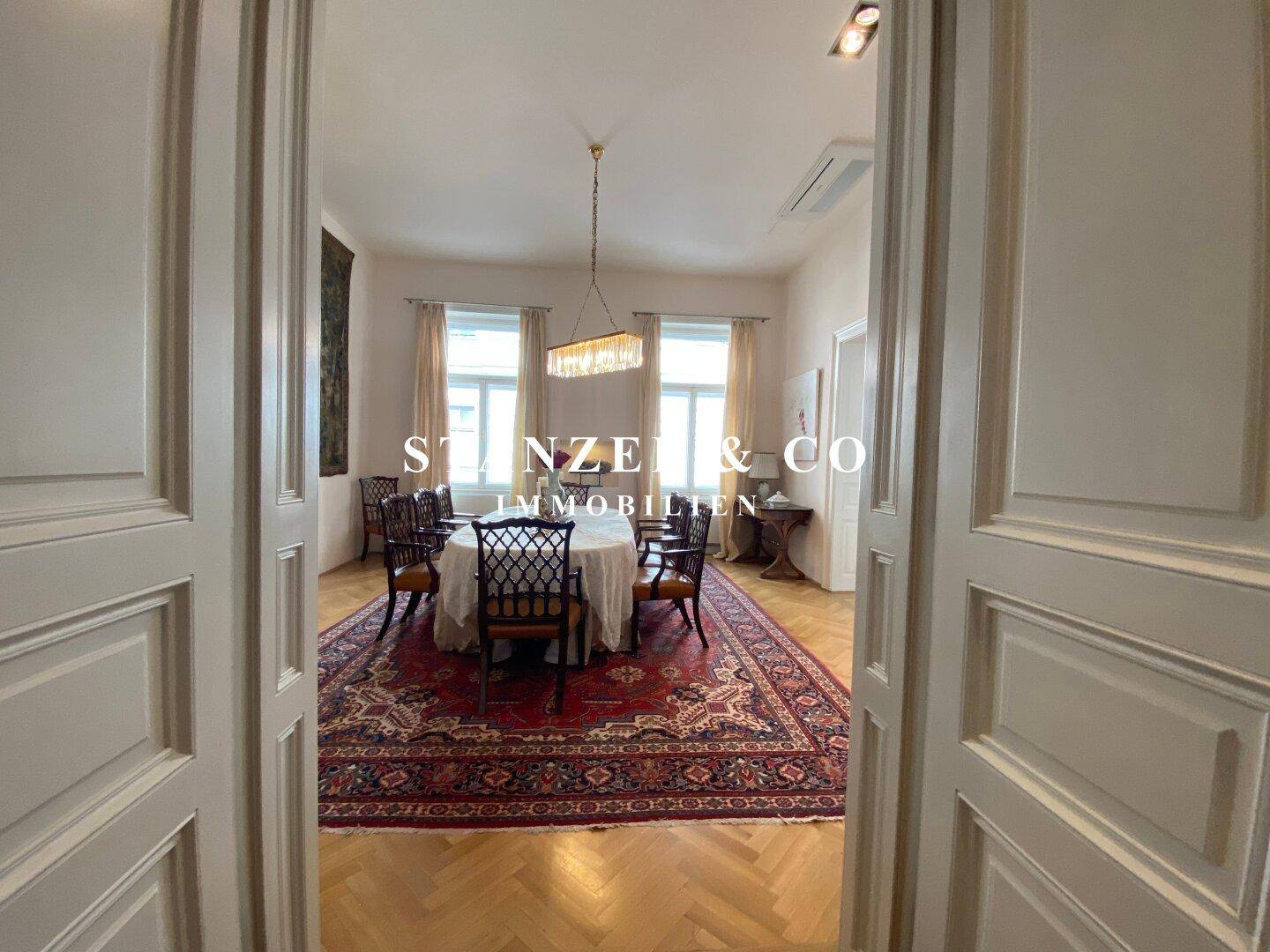 Elegantes Esszimmer mit klassischem Parkettboden, großem Esstisch und Kronleuchter.