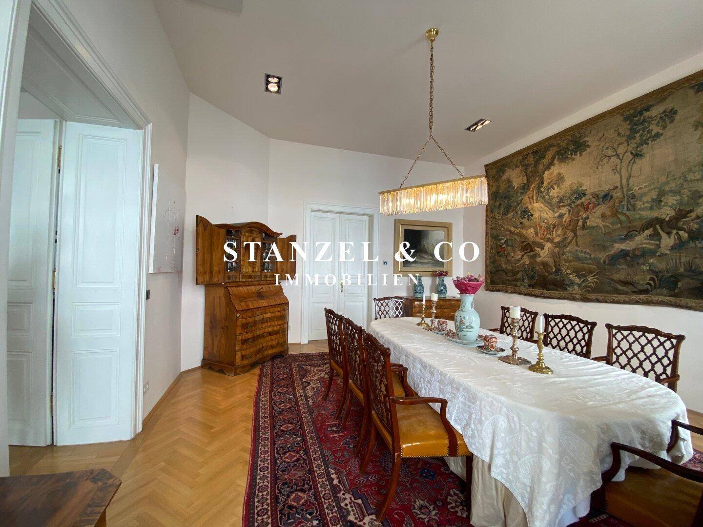 Elegantes Esszimmer mit Parkettboden, antiken Möbeln und einem großen Wandteppich.