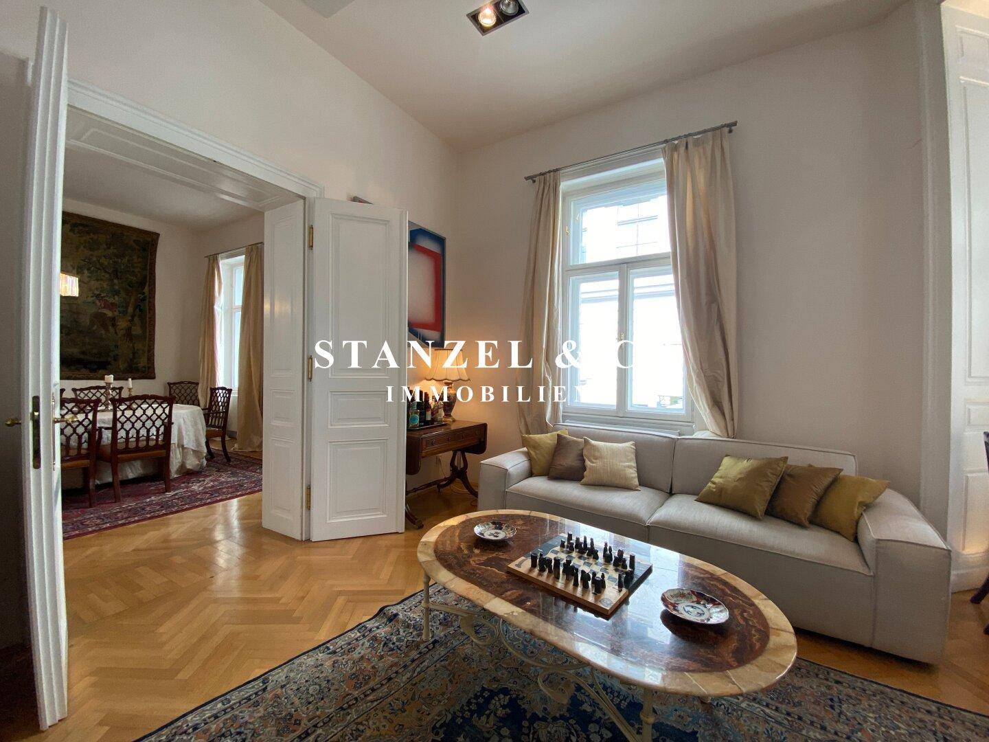 Helles Wohnzimmer mit Parkettboden, bequemen Sofas und Zugang zum Esszimmer.