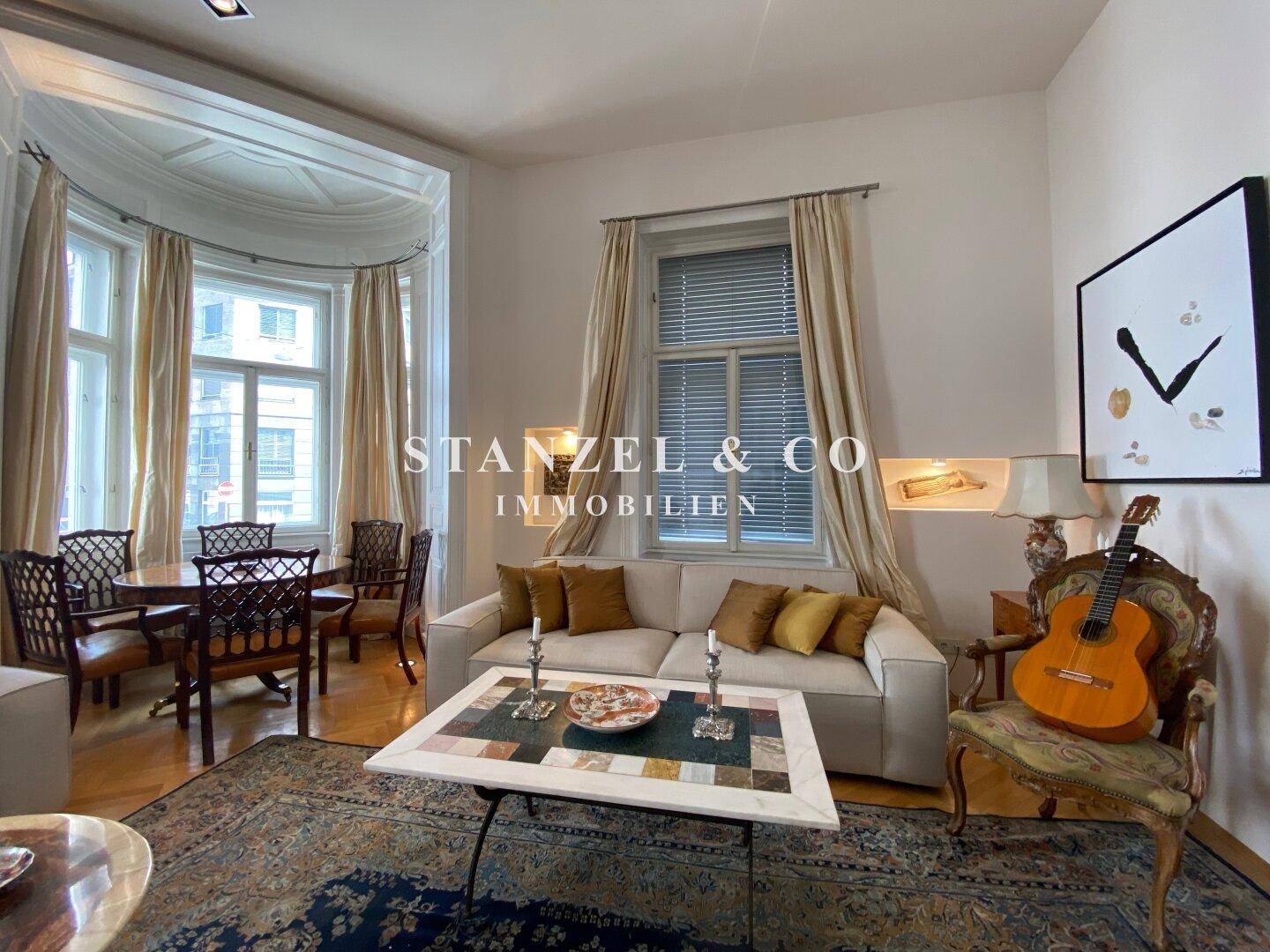 Gemütliches Wohnzimmer mit Sofas, Teppich und einem Erker mit Essbereich.