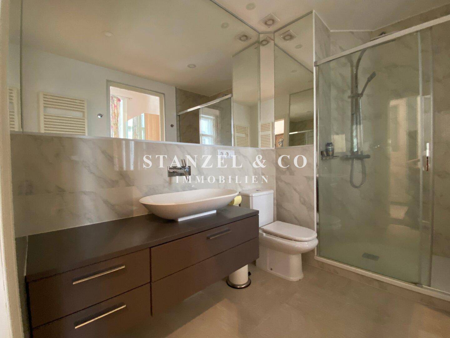 Stilvolles Badezimmer mit Marmorfliesen, Dusche und modernem Waschbecken.