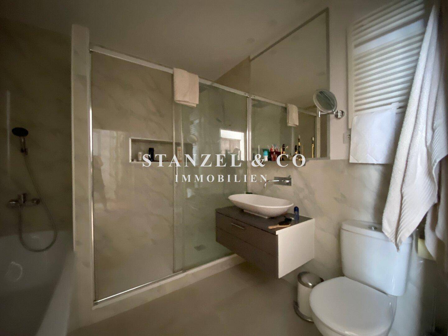 Stilvolles Badezimmer mit Badewanne, Dusche und modernem Waschbecken.