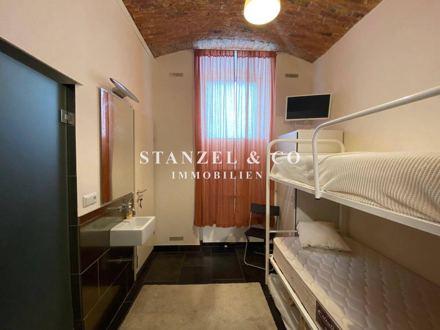 Gemütliches Schlafzimmer mit Etagenbett, Waschbecken und gewölbter Ziegeldecke.