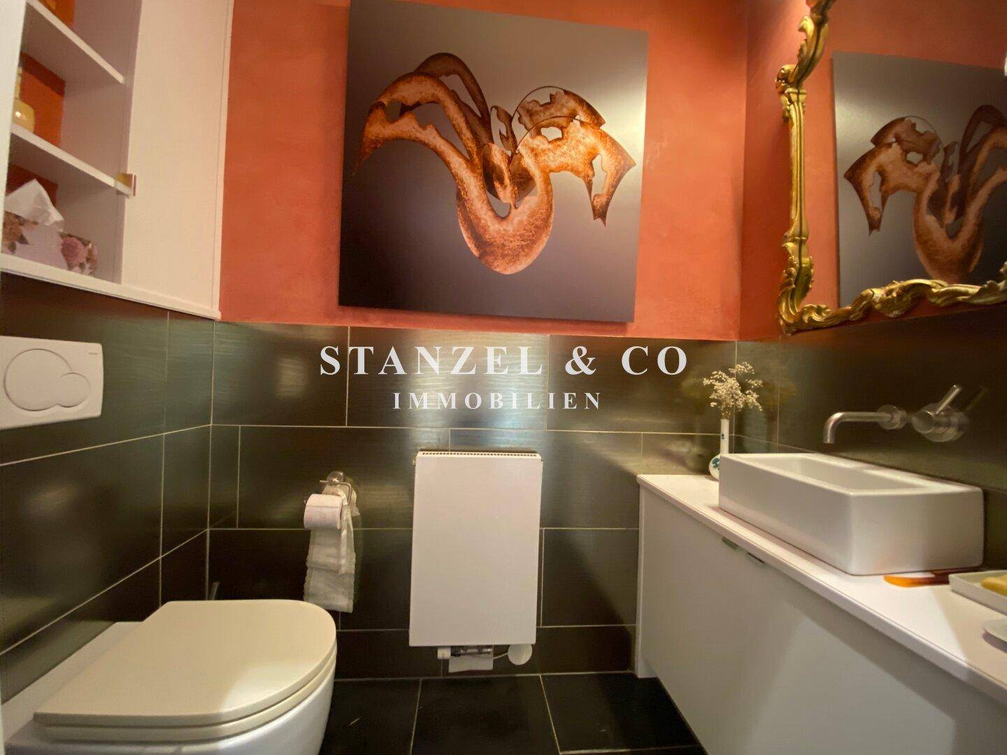 Modernes Gäste-WC mit dunklen Fliesen, Wand-WC und stilvollem Waschbecken.