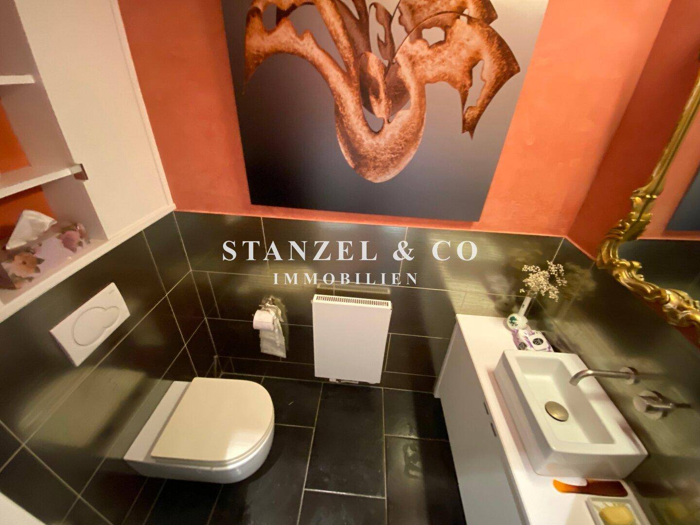 Stilvolles Gäste-WC mit dunklen Fliesen, Wand-WC und modernem Waschbecken.