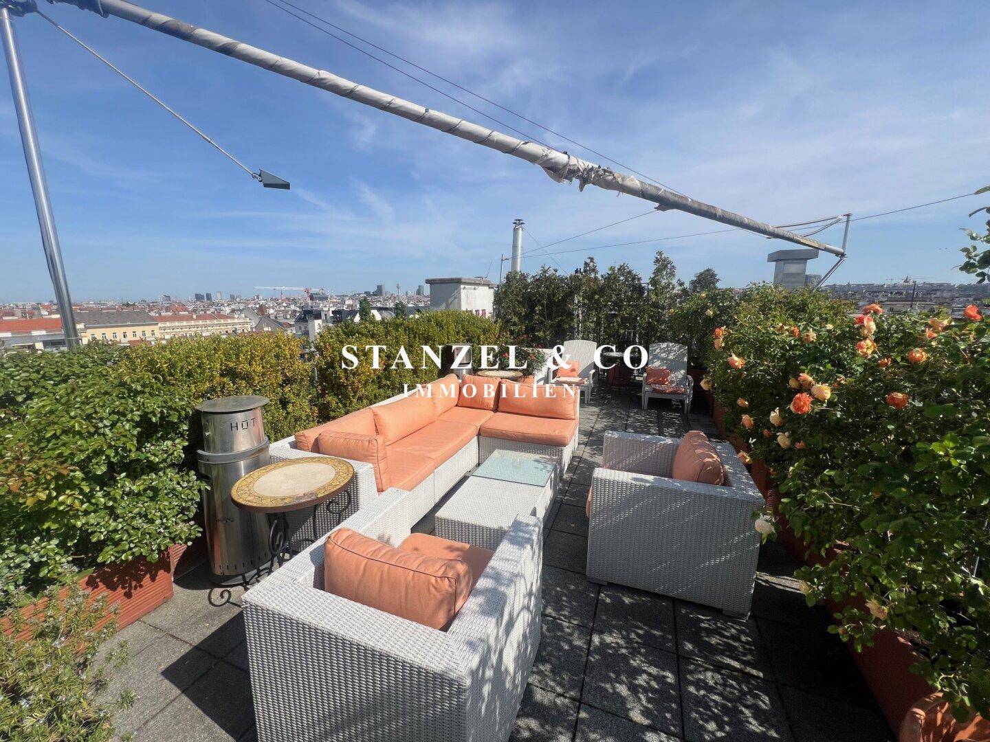 Weitläufige Dachterrasse mit komfortablen Loungemöbeln und vielen Pflanzen in Töpfen.