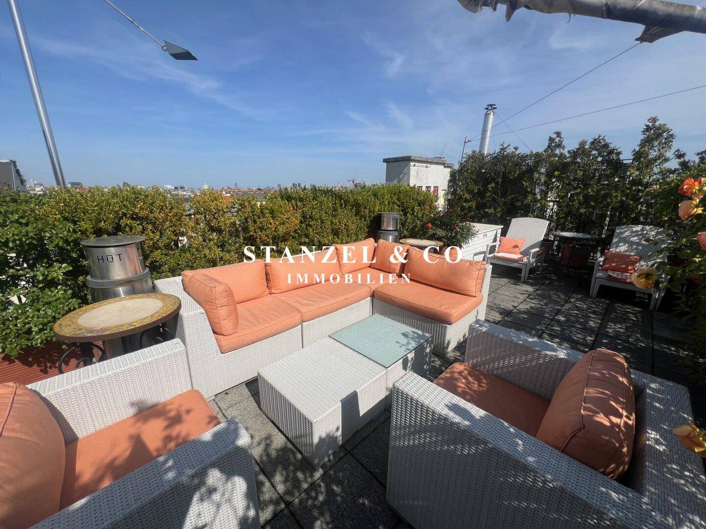 Entspannungsbereich auf der Dachterrasse mit Loungemöbeln, Pflanzen und einem Heizstrahler.