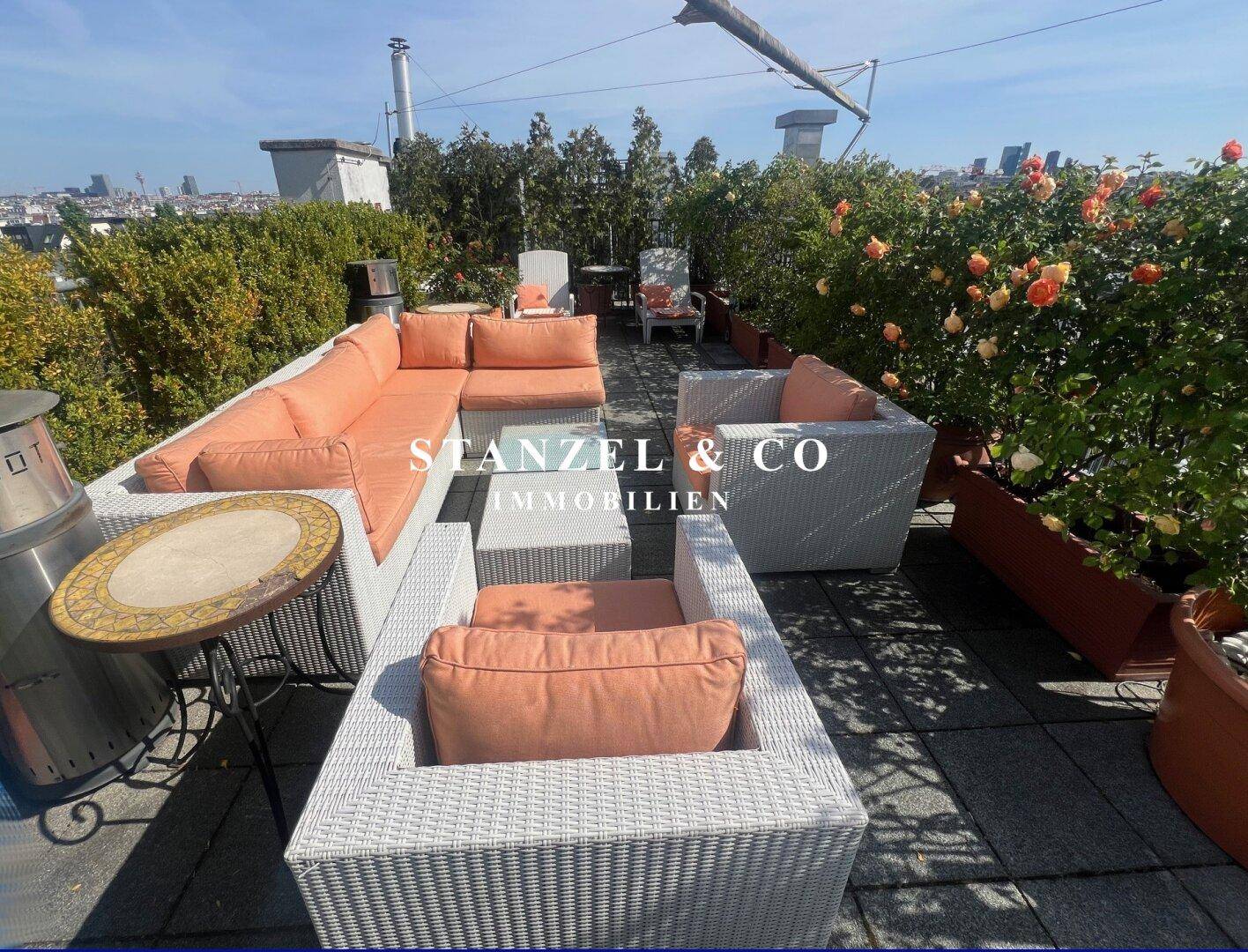 Großzügige Dachterrasse mit bequemen Loungemöbeln, Pflanzen und einem dekorativen Beistelltisch.