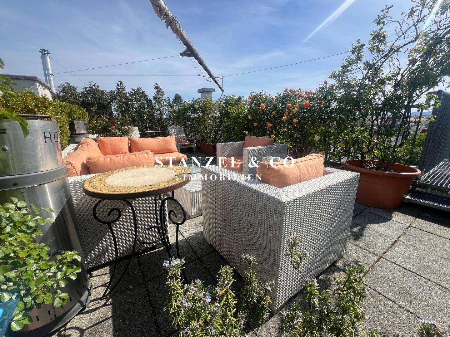 Gemütliche Dachterrasse mit Loungemöbeln, Pflanzen und einem Heizstrahler für kühle Abende.
