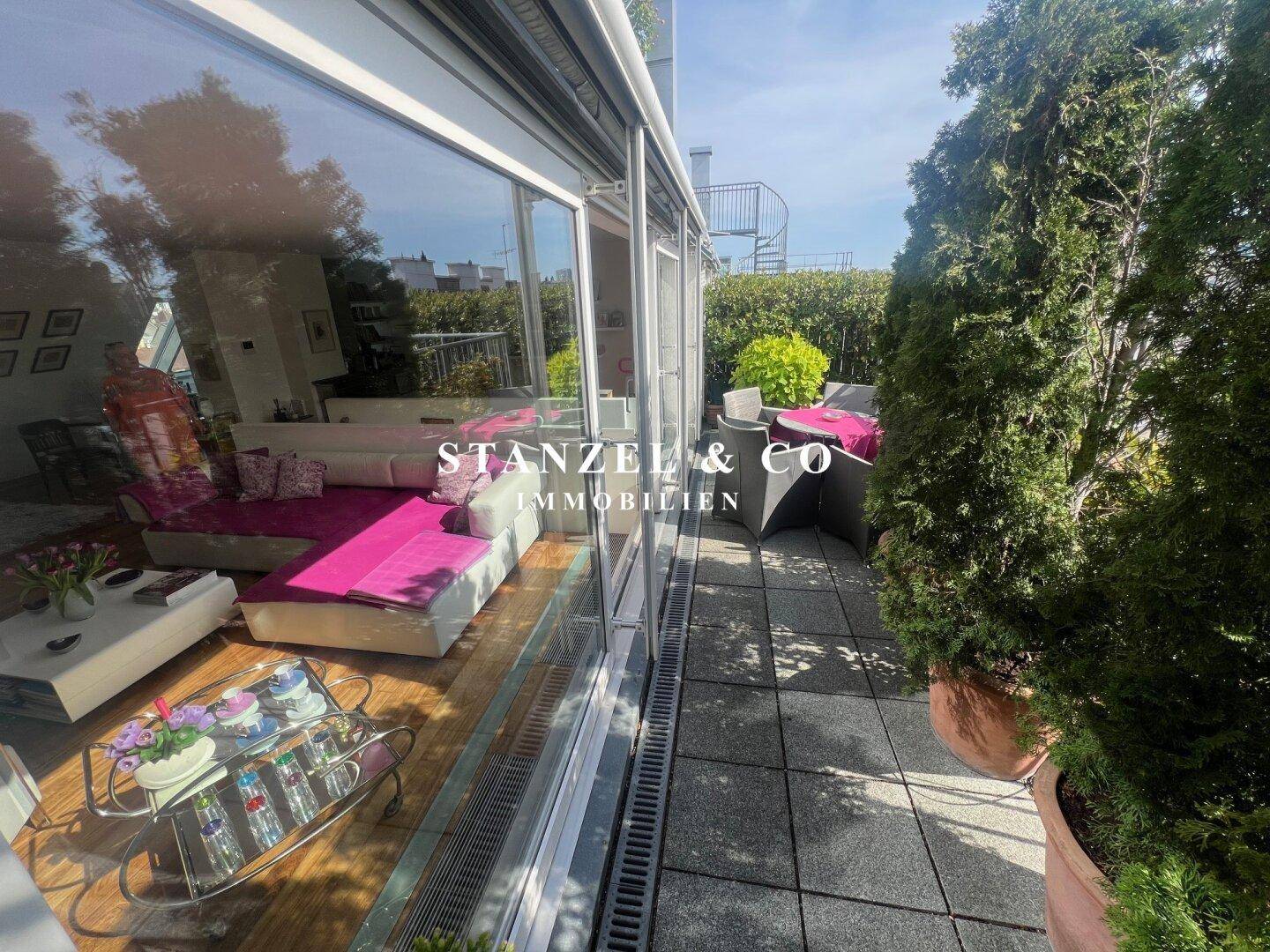 Teil der Dachterrasse mit Esstisch und Blick in den hellen Wohnbereich durch große Fenster.