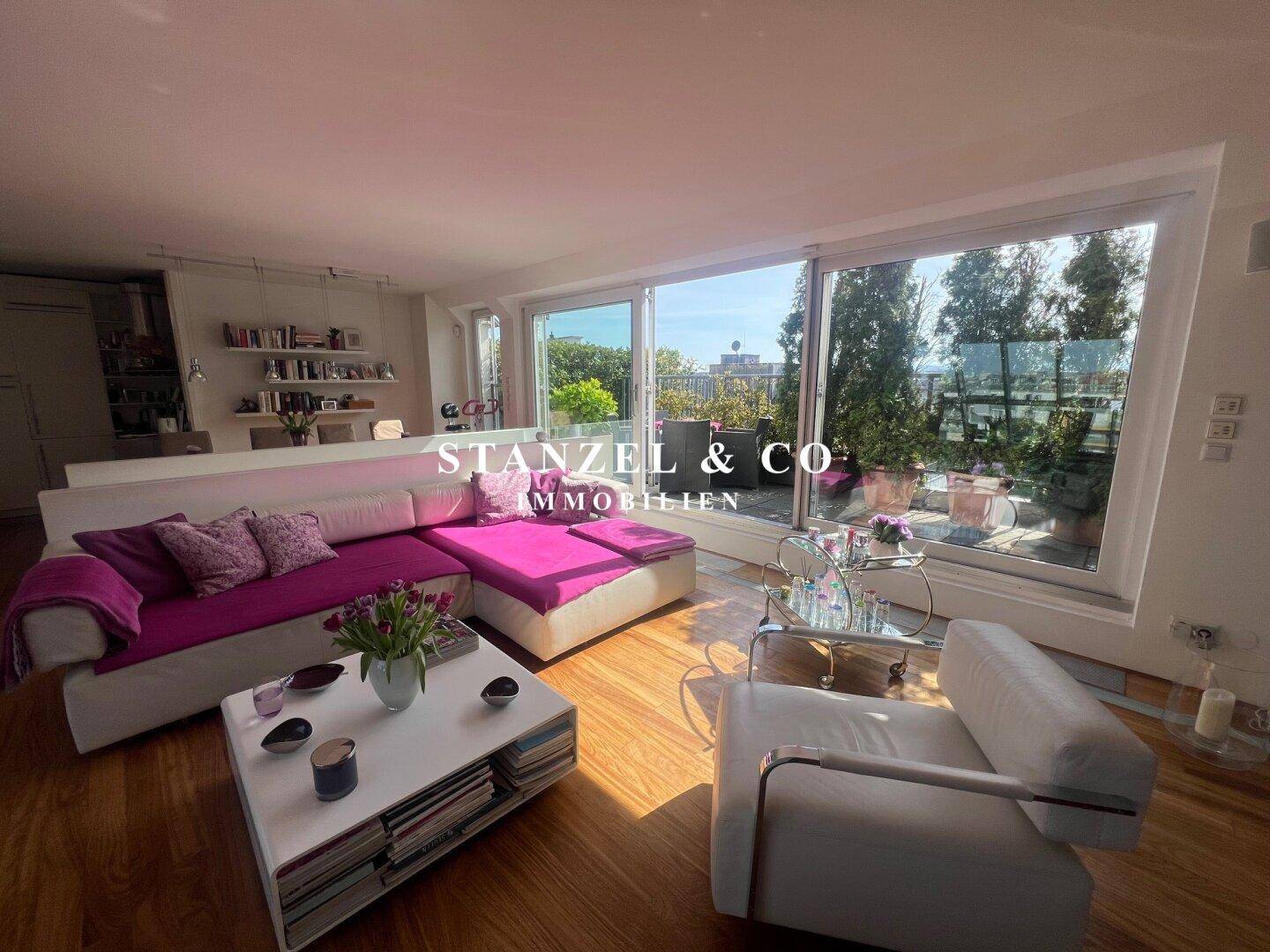 Helles Wohnzimmer mit Holzboden, großer Couch und direktem Zugang zur sonnigen Dachterrasse.