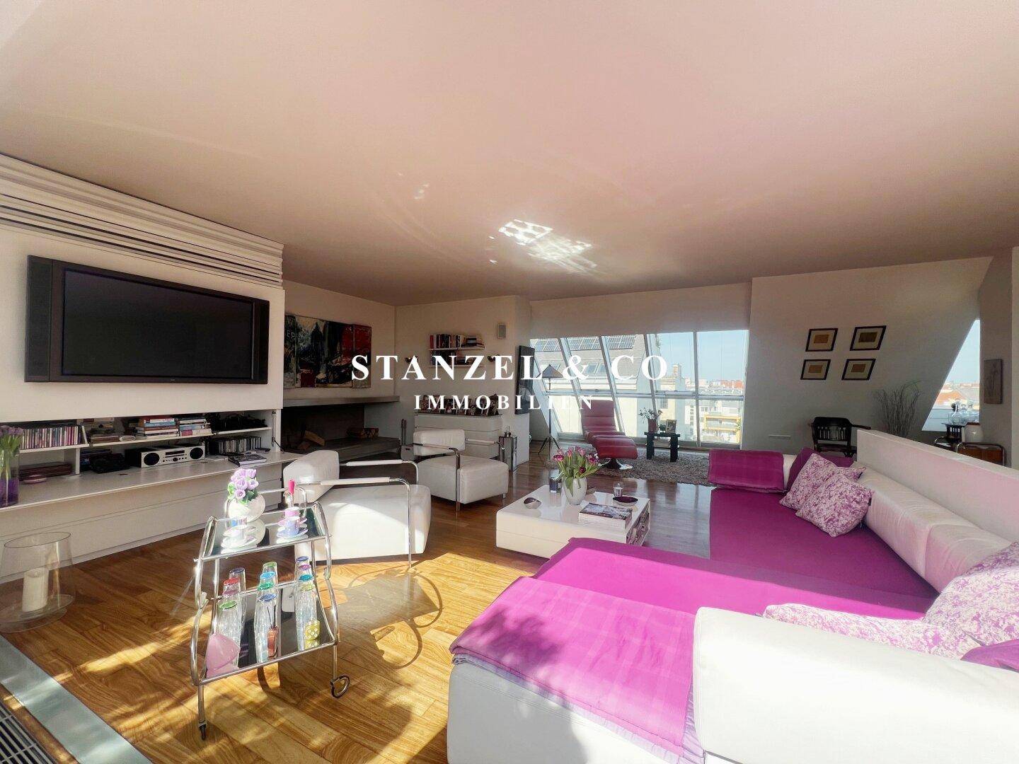 Helles Wohnzimmer mit Holzboden, großer Couch und direktem Zugang zur sonnigen Dachterrasse.