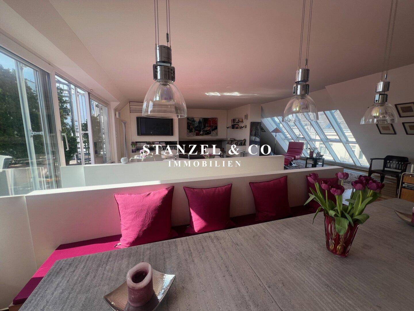 Essbereich mit langem Holztisch und Stühlen, offen zur Küche und mit Blick auf die Stadt.