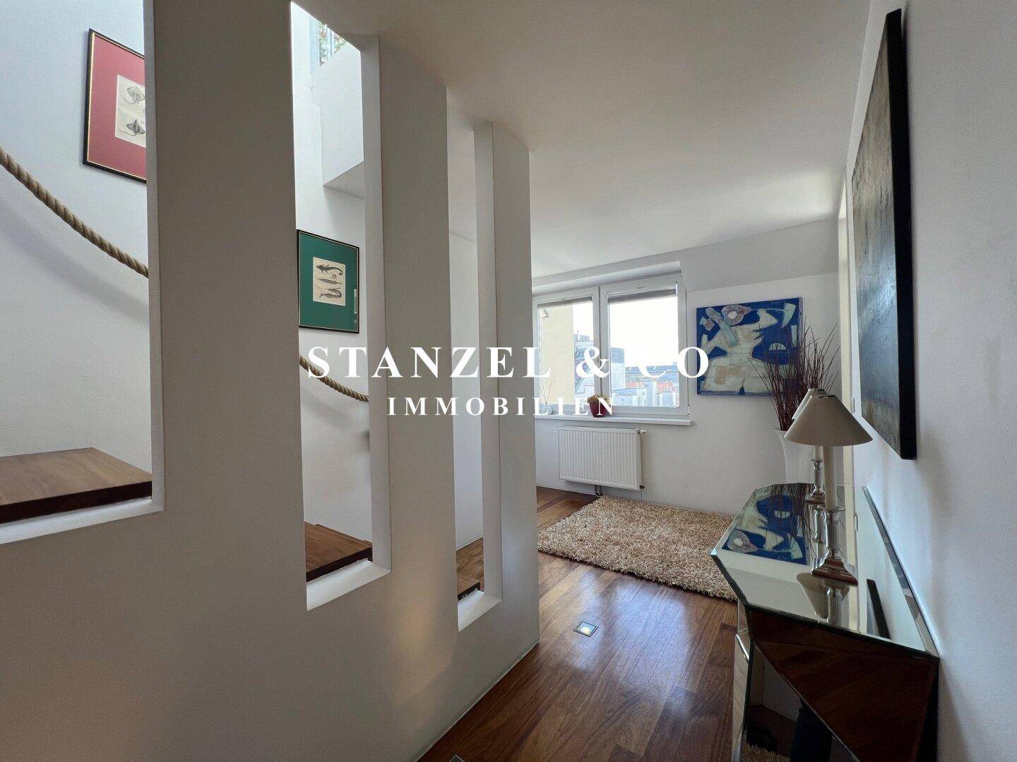 Helles Arbeitszimmer mit Holzboden, Schreibtisch und Sofa, ideal für Home-Office.