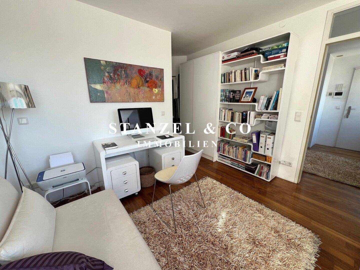 Arbeitszimmer mit Holzboden, Schreibtisch und Bücherregal, bietet eine funktionale Arbeitsumgebung.