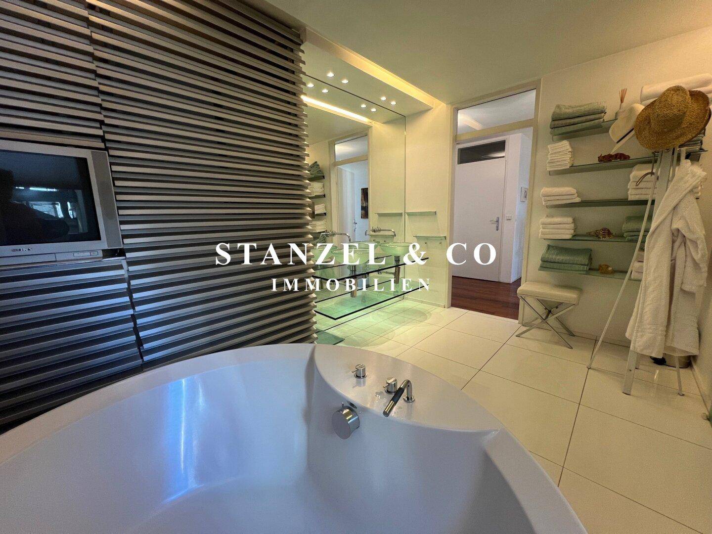 Modernes Badezimmer mit runder Badewanne, Doppelwaschbecken und beheiztem Handtuchhalter.