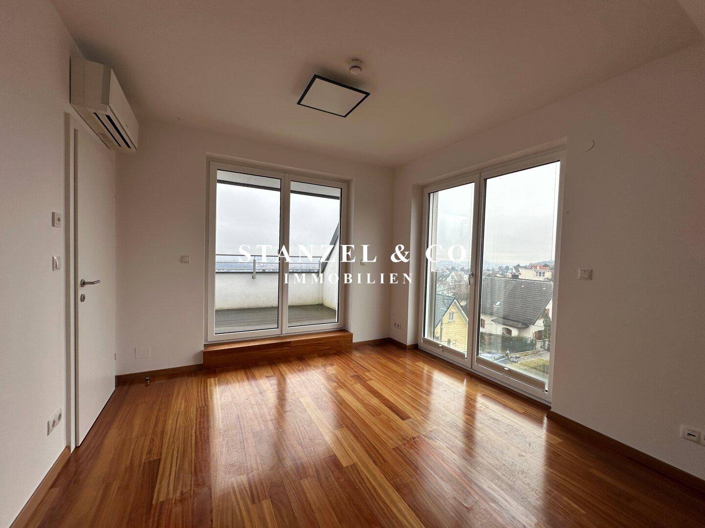 Schlafzimmer mit Holzboden, Klimaanlage und direktem Zugang zum Balkon.