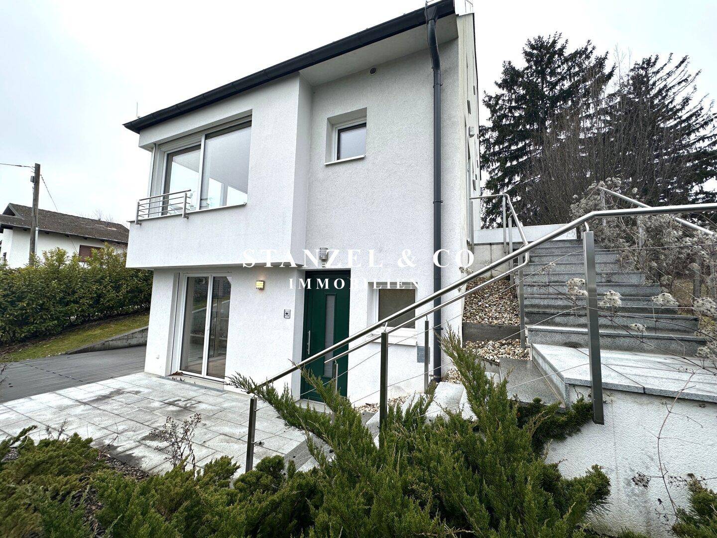 Vorderansicht des modernen Hauses mit weißer Fassade und Eingangsbereich.