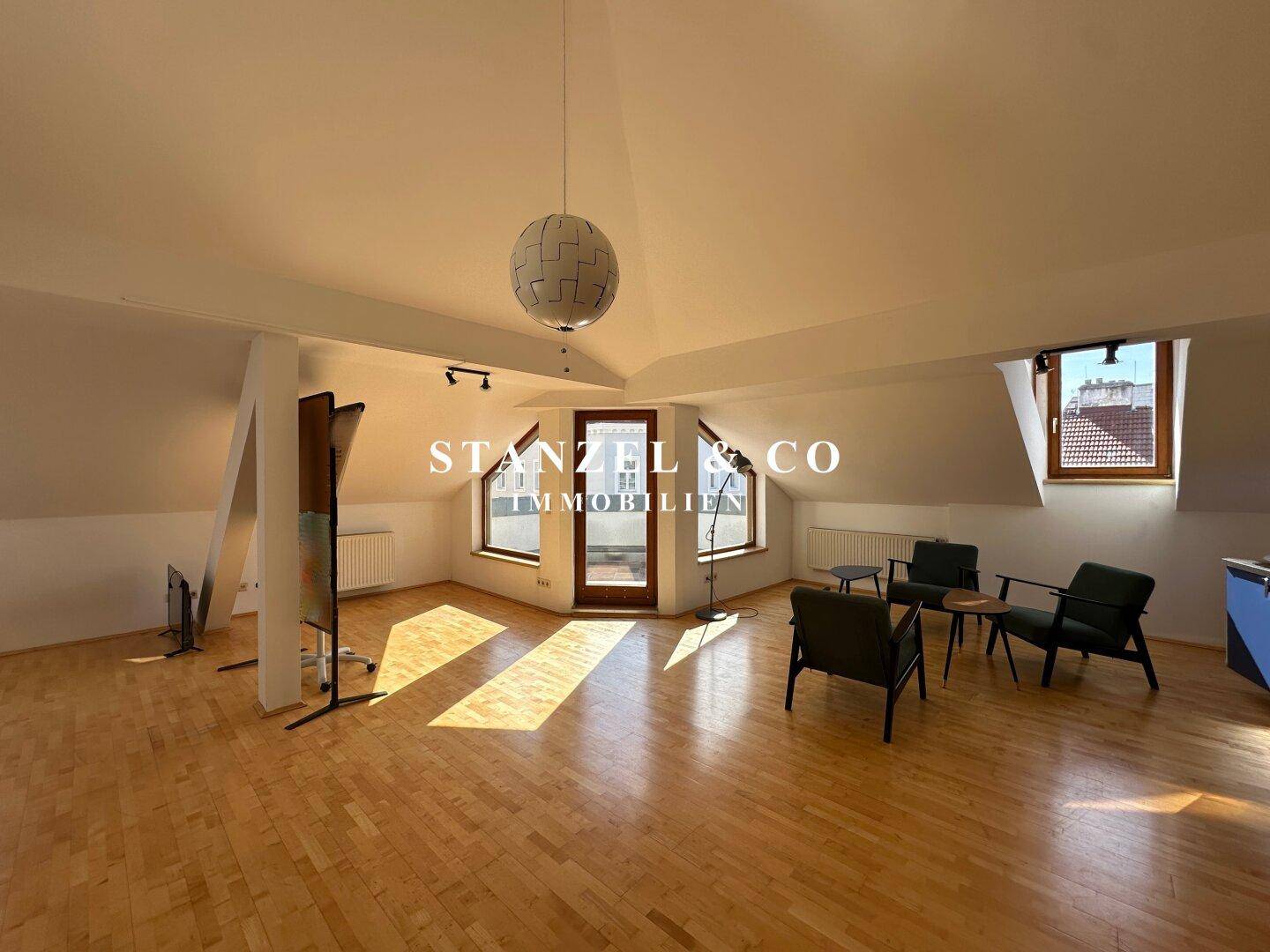 Helles und geräumiges Wohnzimmer im Dachgeschoss mit Holzboden, schrägen Decken und viel Tageslicht.