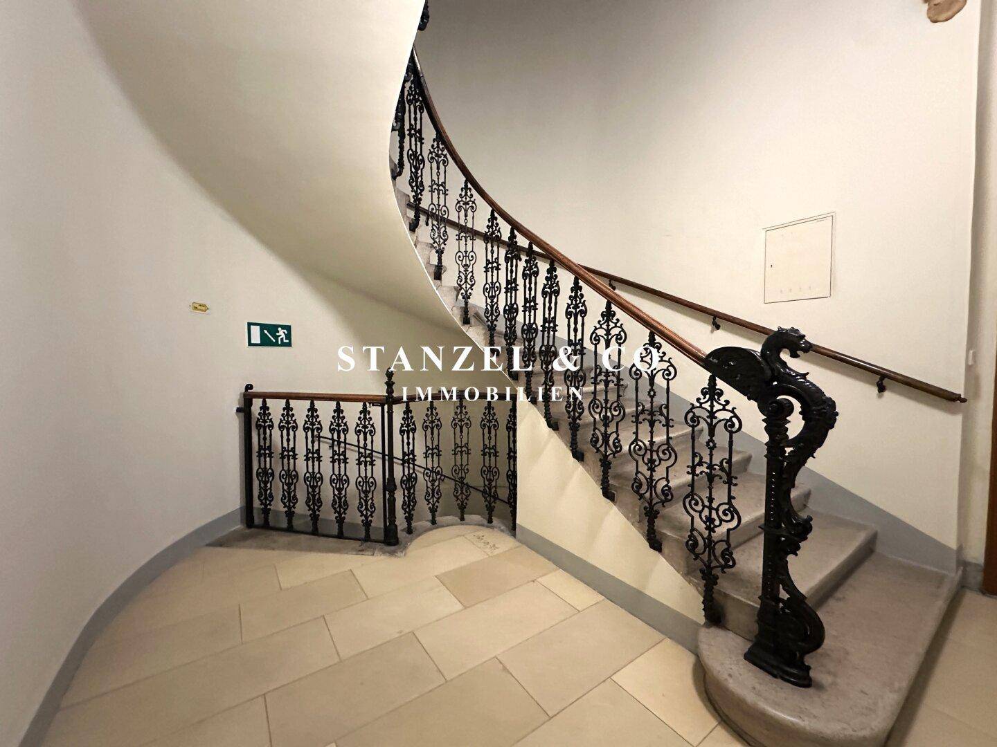 Historische Wendeltreppe mit kunstvollem schmiedeeisernem Geländer und Steinstufen.