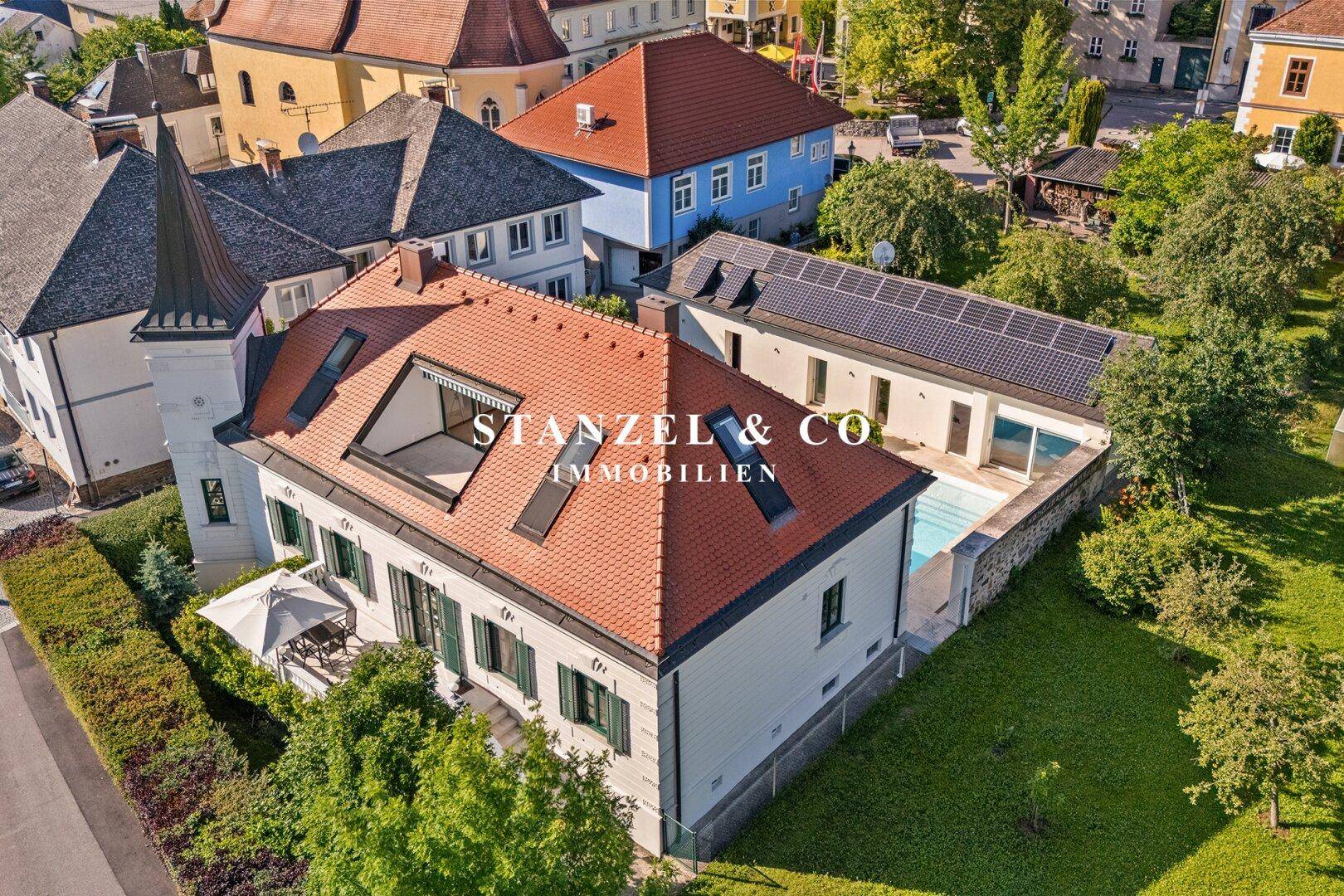 Vogelperspektive der Villa mit Pool, Photovoltaikanlage und gepflegtem Gartenbereich.