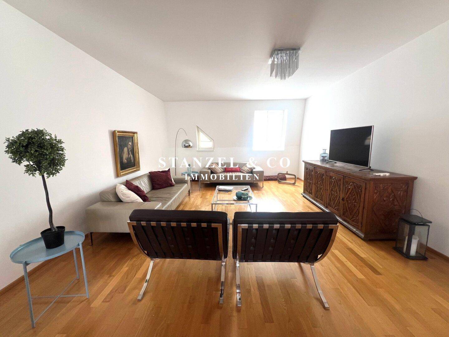 Gemütliches Wohnzimmer mit bequemen Sitzgelegenheiten, Holzboden und moderner Dekoration.