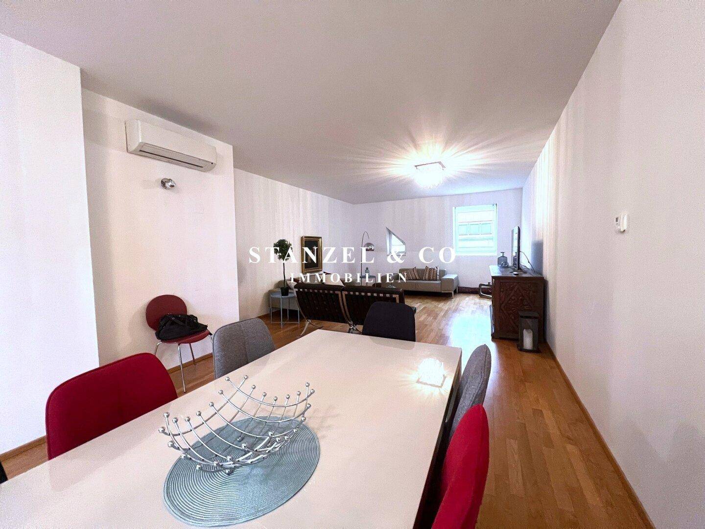 Essbereich mit großem Tisch und farbigen Stühlen, offen zum Wohnzimmer und mit Klimaanlage.