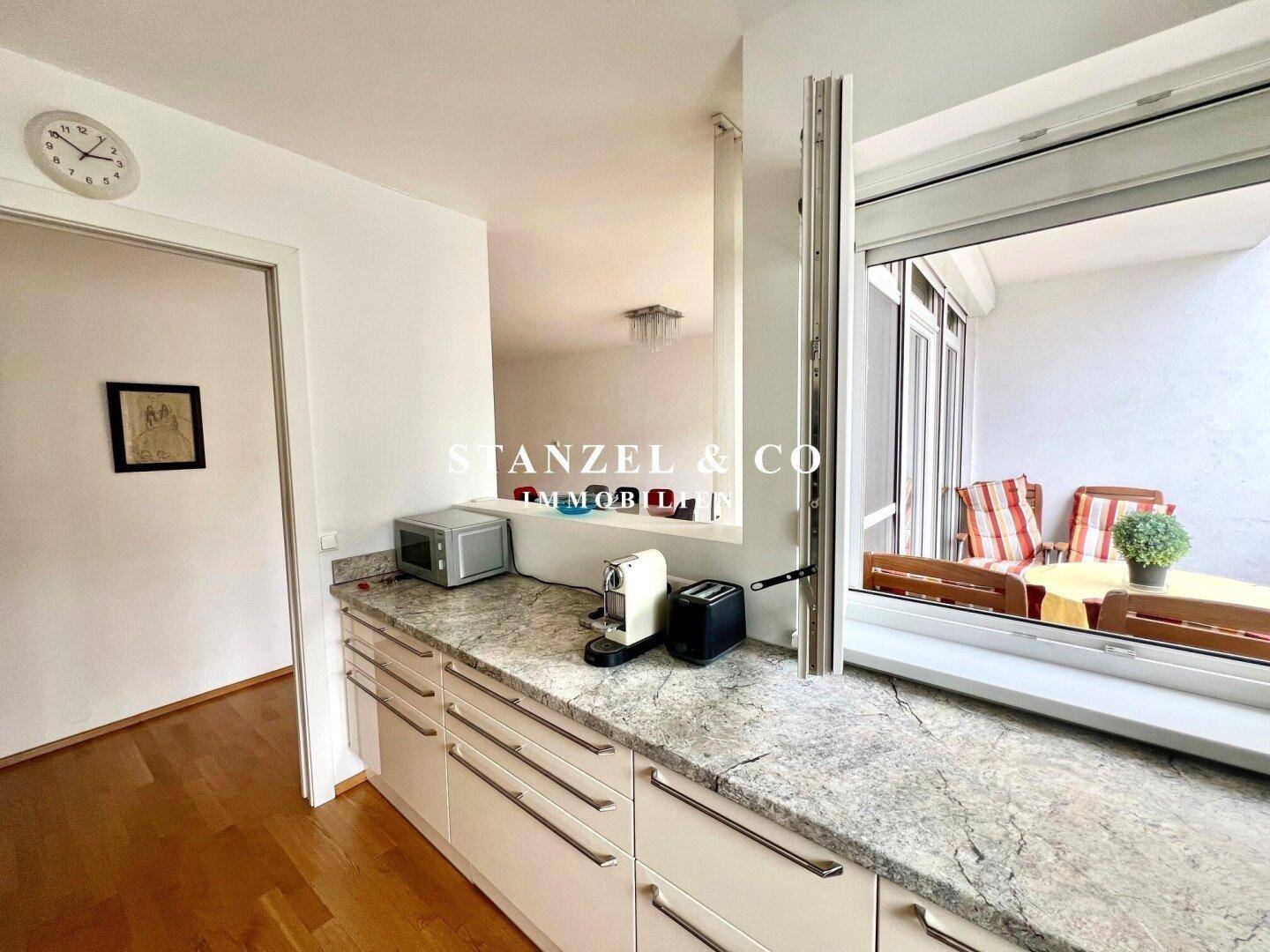 Funktionale Küche mit Granitarbeitsplatte und praktischem Durchgang zum Balkon.