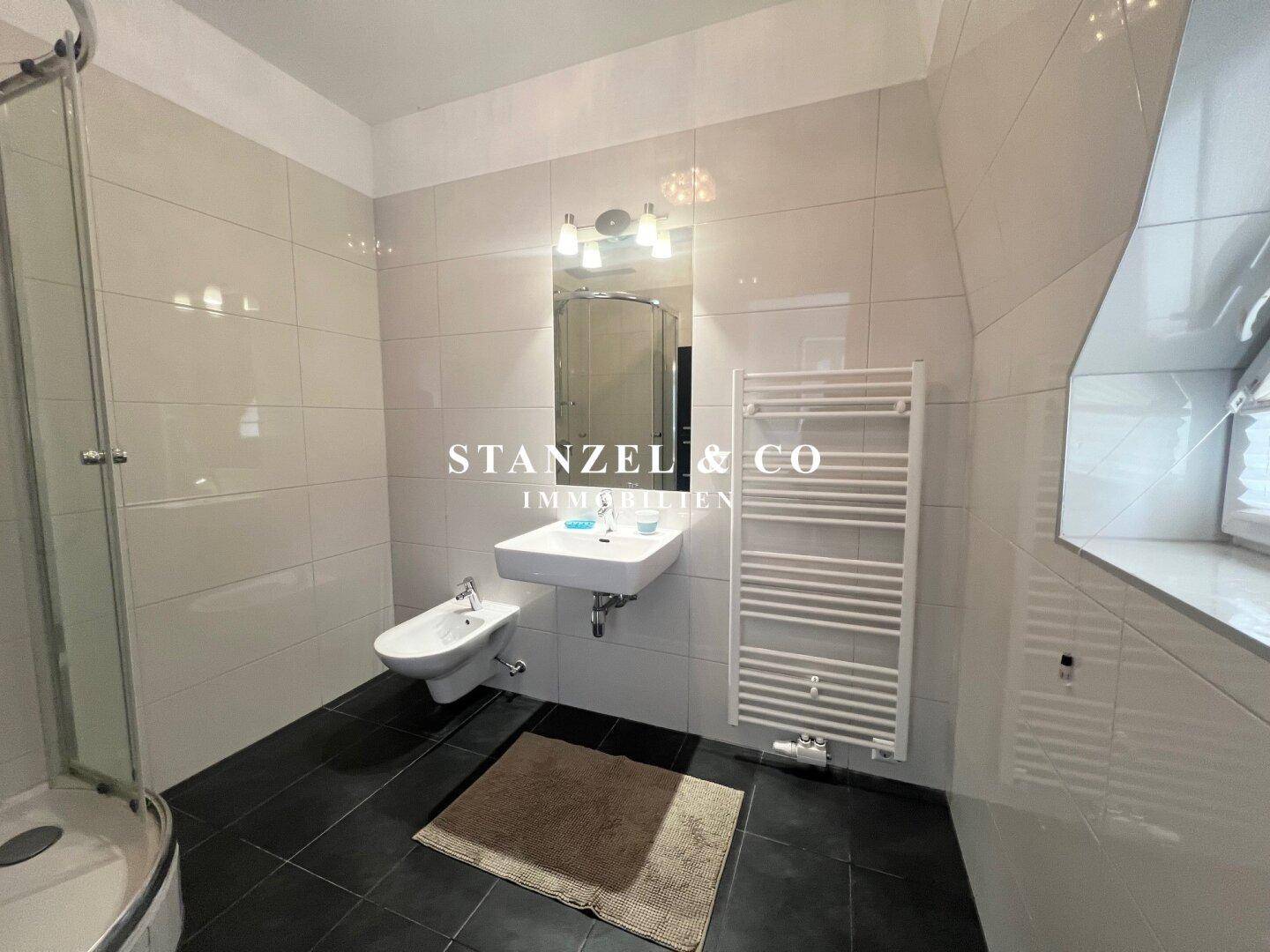 Badezimmer mit Dusche, Einzelwaschbecken, Bidet und beheiztem Handtuchhalter.