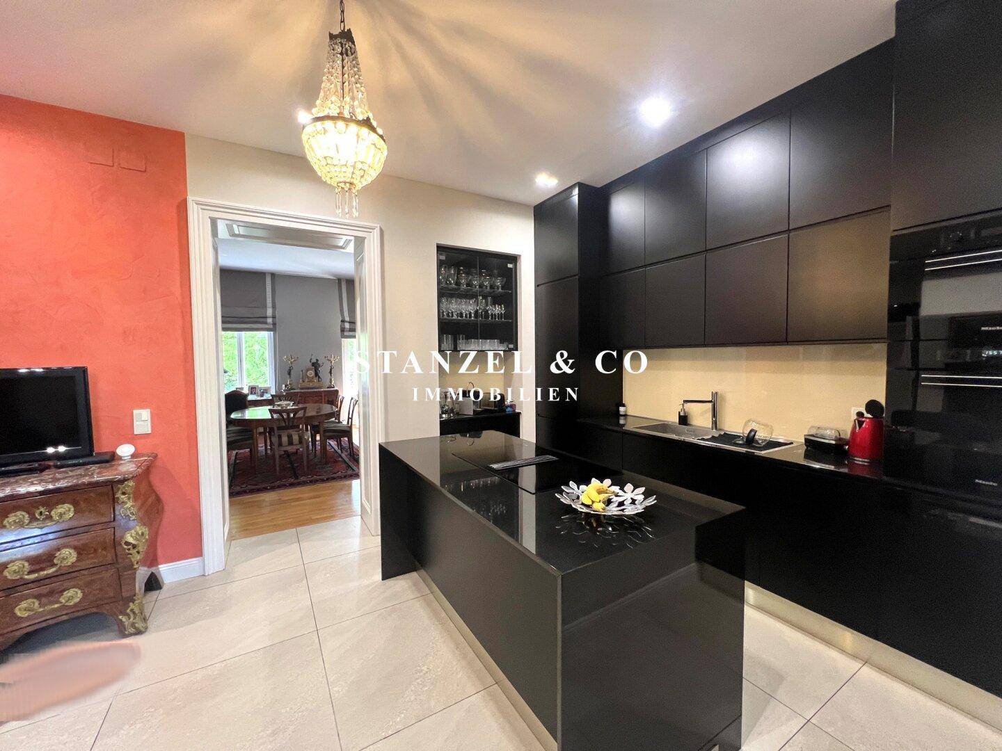 Moderne schwarze Küche mit Kochinsel und Durchgang zum eleganten Esszimmer.