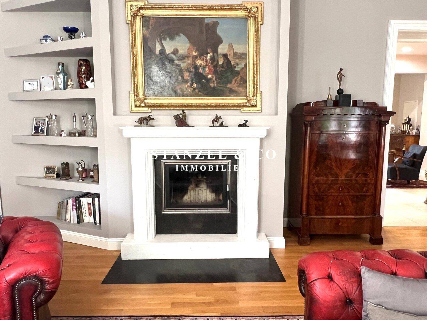 Detailansicht des eleganten Kamins mit Kunstwerk und integrierten Regalen im Wohnzimmer.