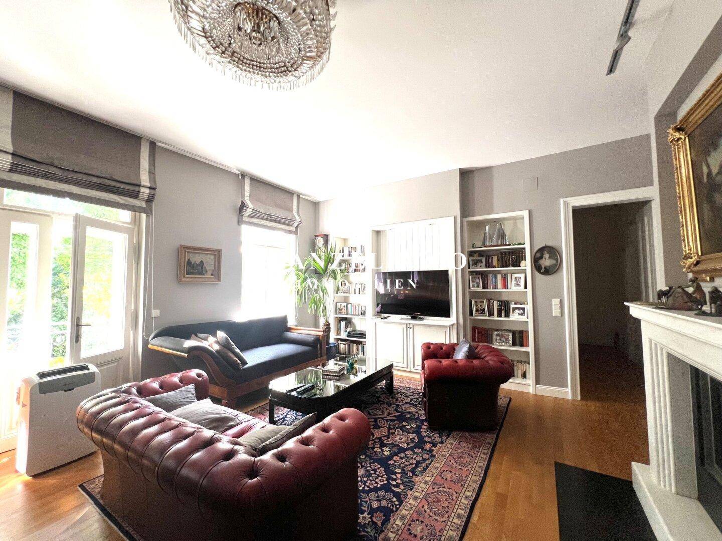 Großzügiges Wohnzimmer mit Kronleuchter, bequemen Sofas und Zugang zum Balkon.