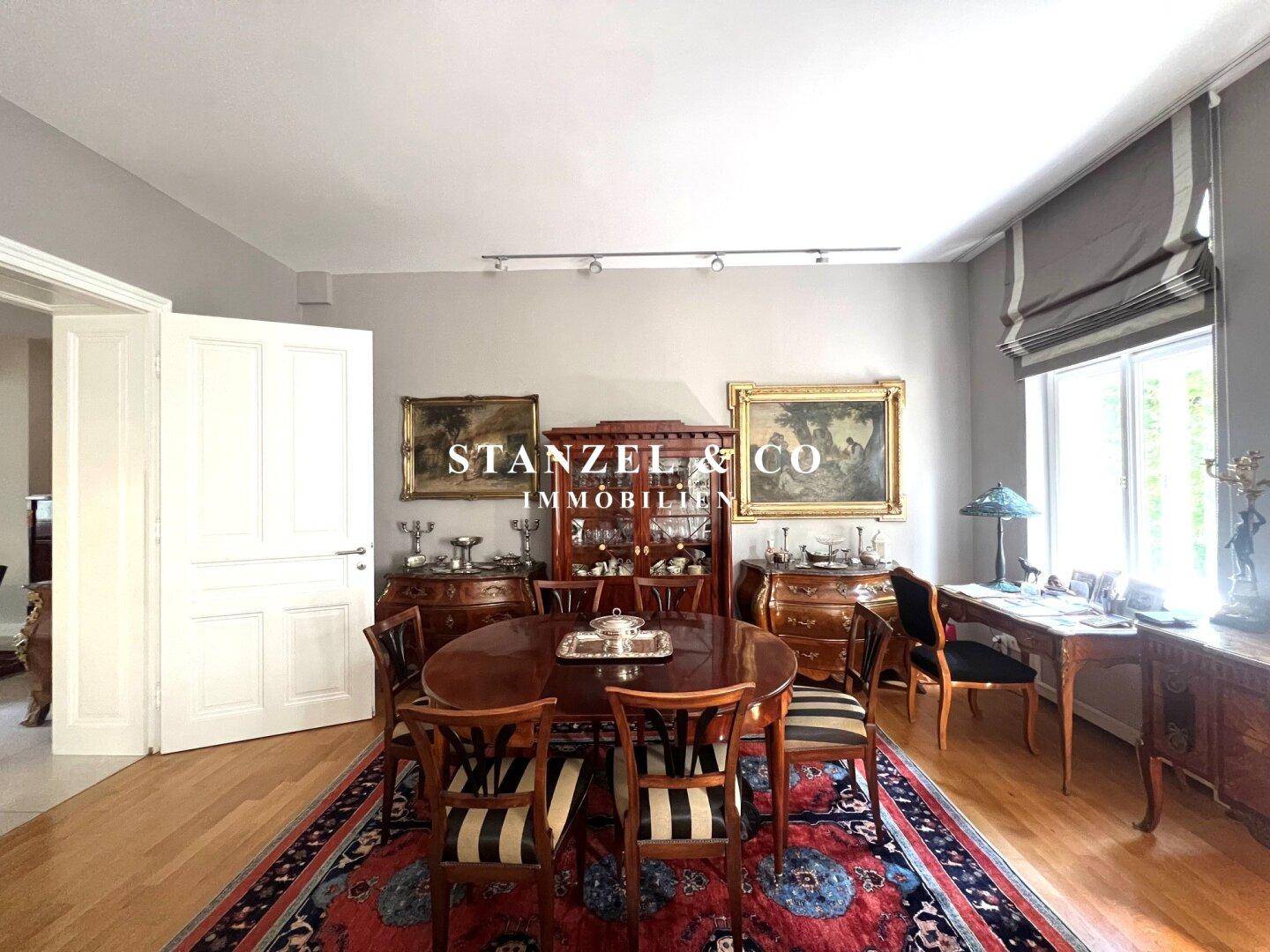 Elegantes Esszimmer mit großem ovalen Esstisch und antiken Holzmöbeln.