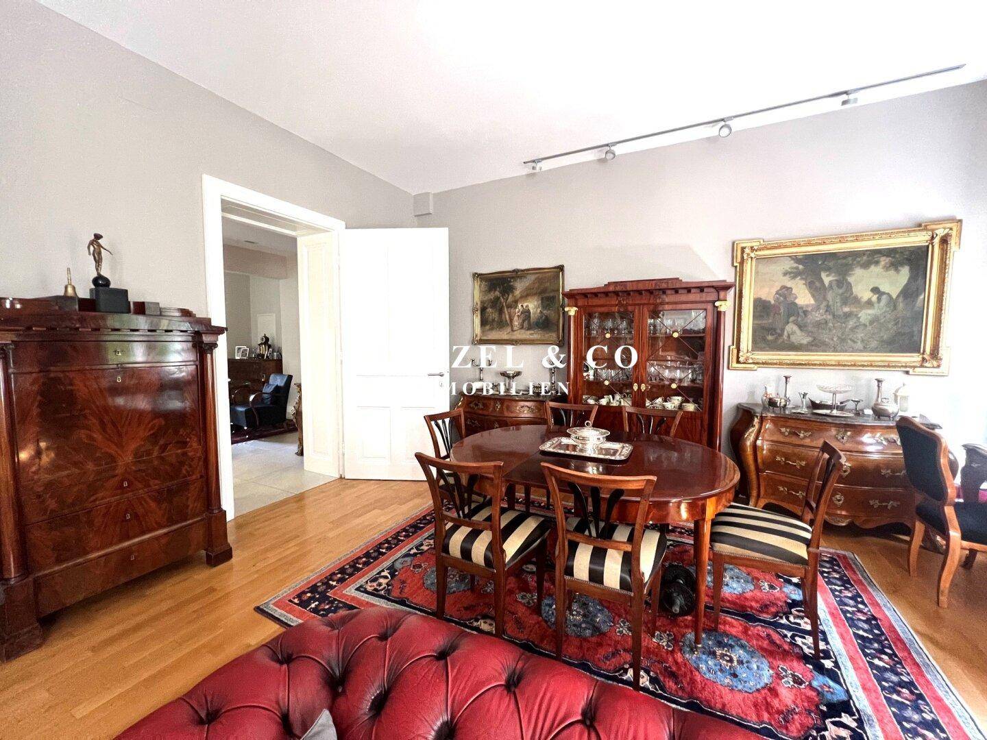 Klassisches Esszimmer mit Holztisch und Stühlen, umgeben von antiken Schränken.