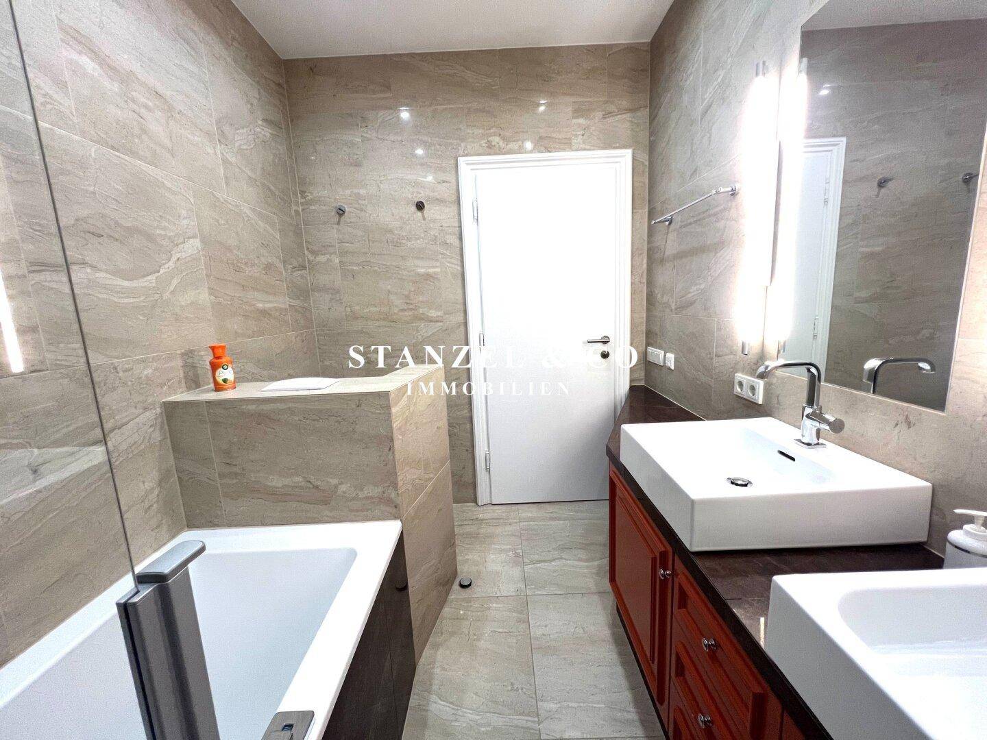 Modernes Badezimmer mit Badewanne, eleganten Fliesen und einem einzelnen Waschbecken.