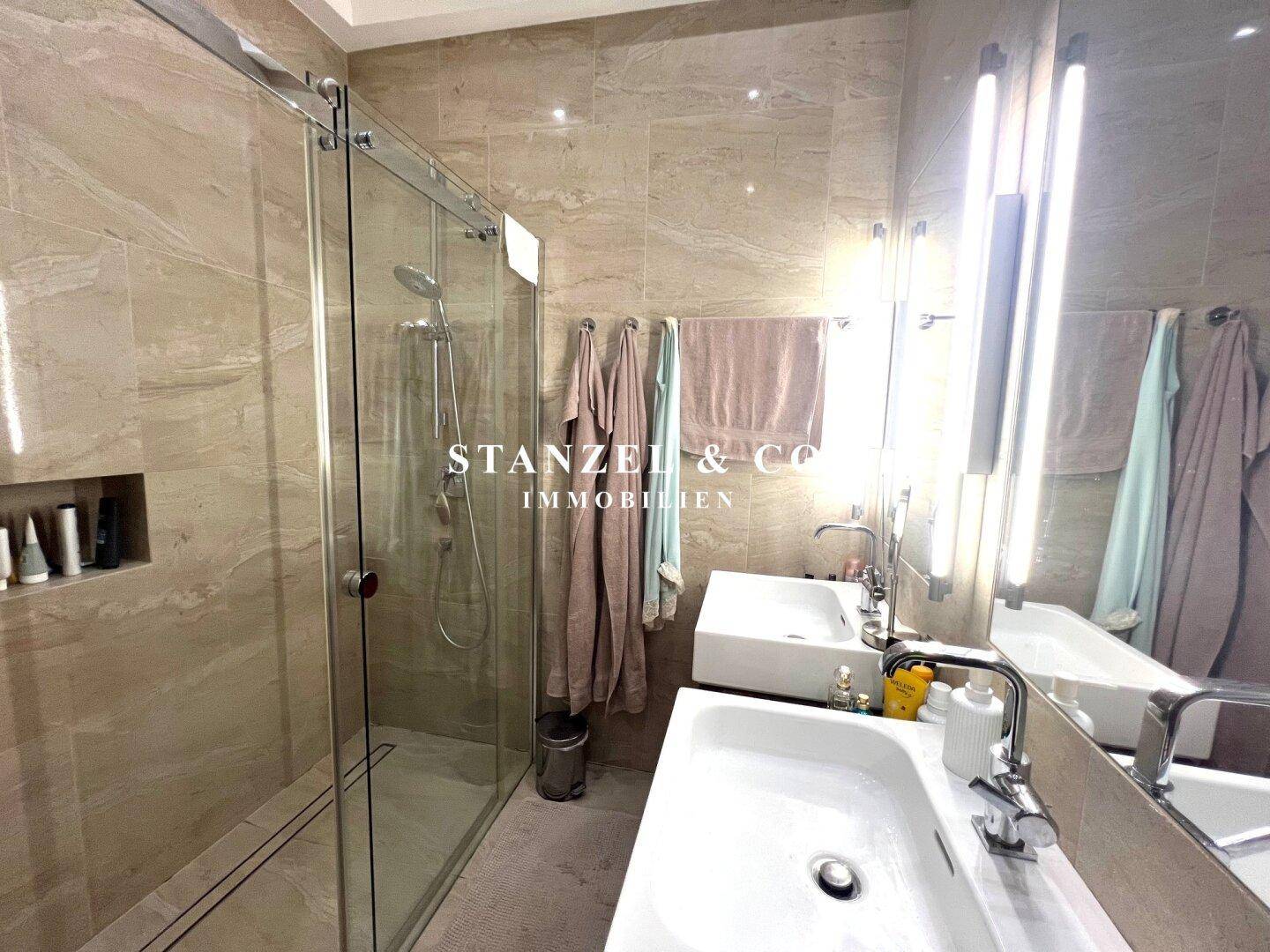 Elegantes Badezimmer mit begehbarer Dusche und zwei stilvollen Waschbecken.