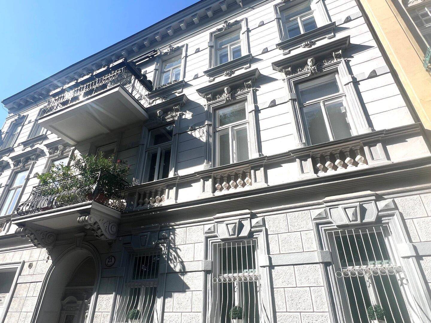 Detailansicht der historischen Fassade mit Stuckverzierungen und einem eleganten Balkon.