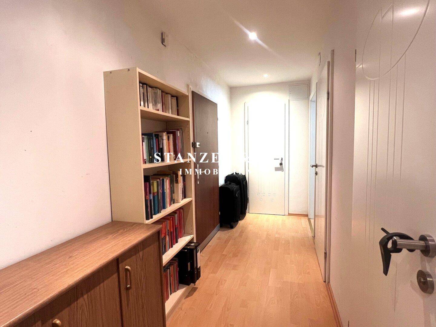 Heller Flur mit Holzmöbeln und einem Bücherregal.