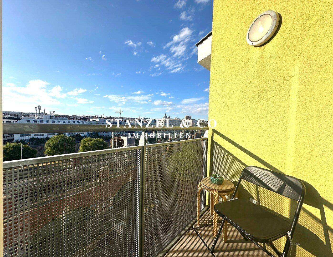 Kleiner Balkon mit einfacher Bestuhlung und Blick auf die umliegenden Gebäude der Stadt.