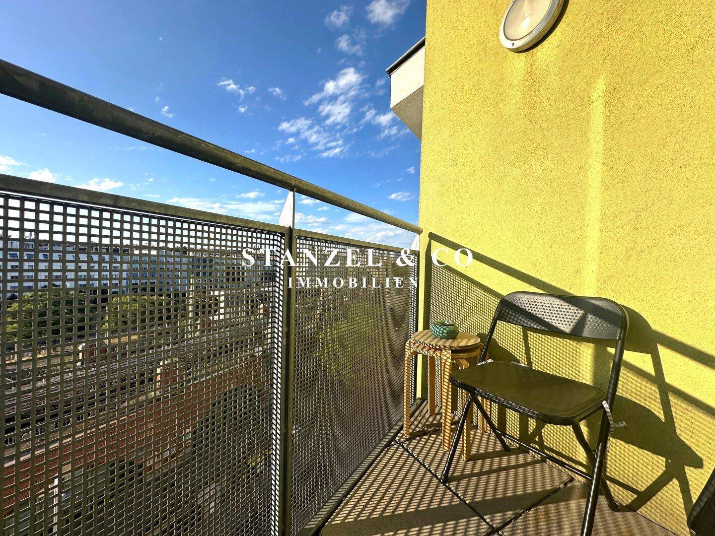 Gemütlicher Balkon mit Sitzgelegenheit und weitem Blick über die städtische Umgebung.
