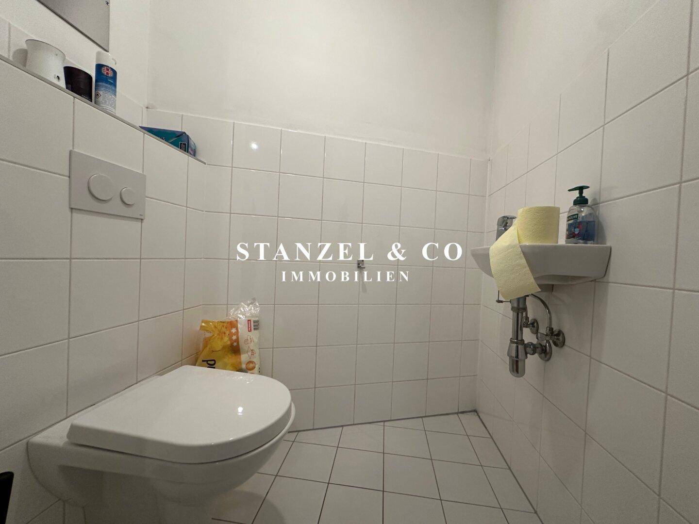 Separates Gäste-WC mit Toilette und kleinem Handwaschbecken, komplett gefliest.