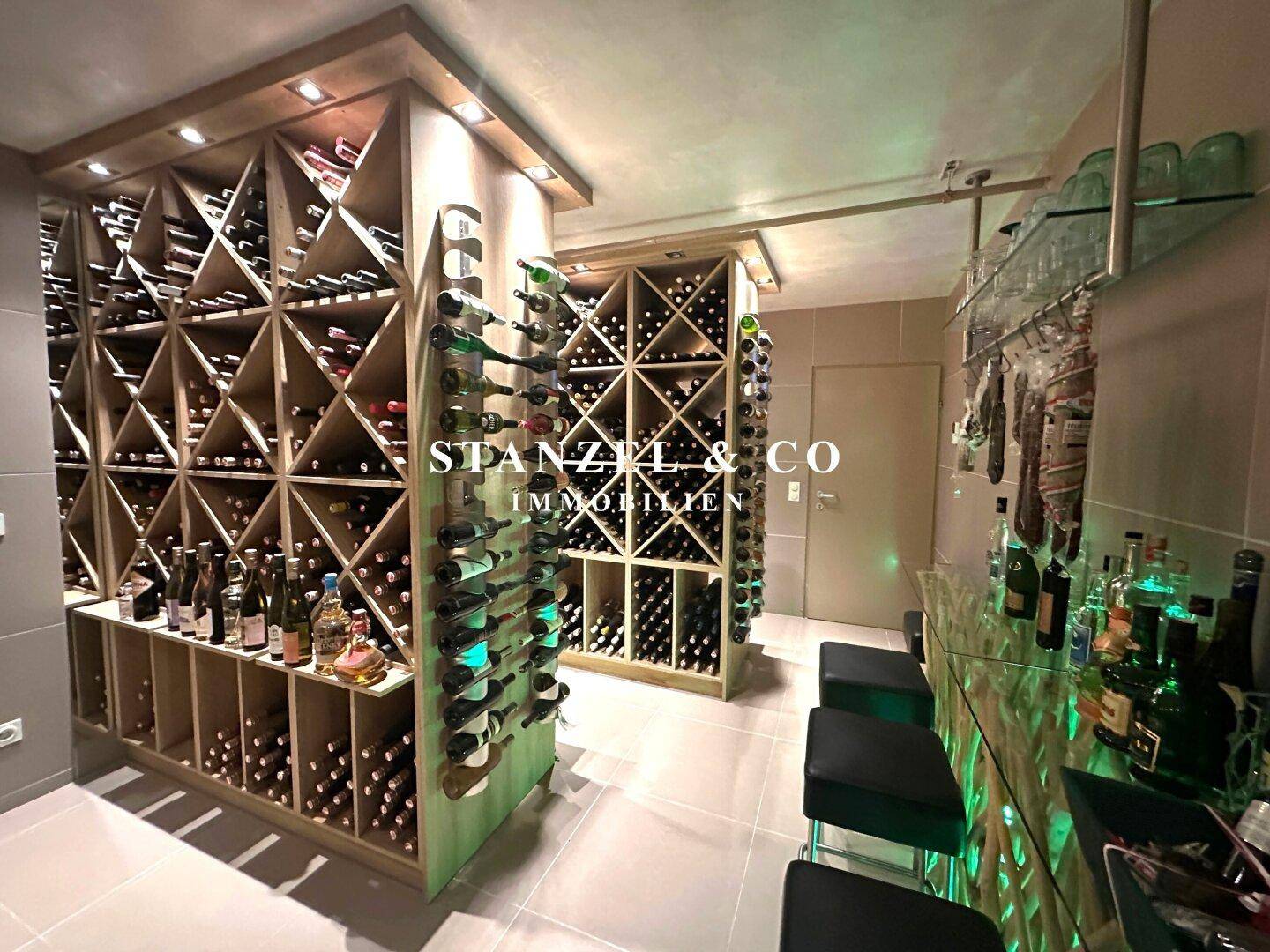 Weiterer Blick in den Weinkeller mit zahlreichen Weinregalen und einer beleuchteten Bar.