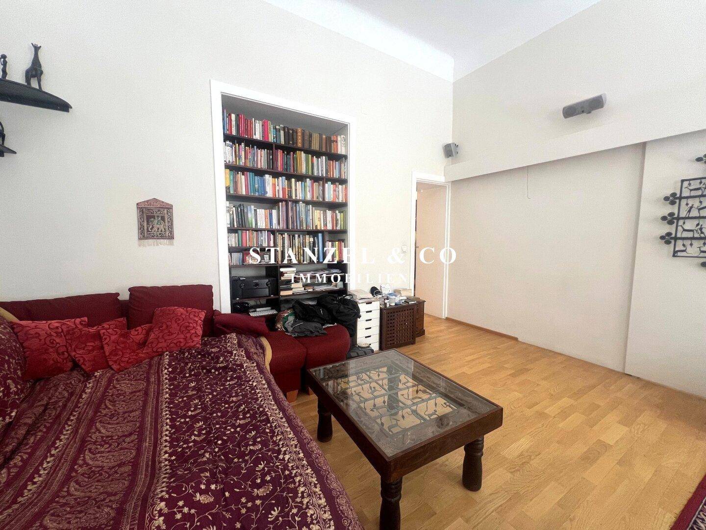 Gemütliches Wohnzimmer mit rotem Sofa, eingebautem Bücherregal und Holzboden.