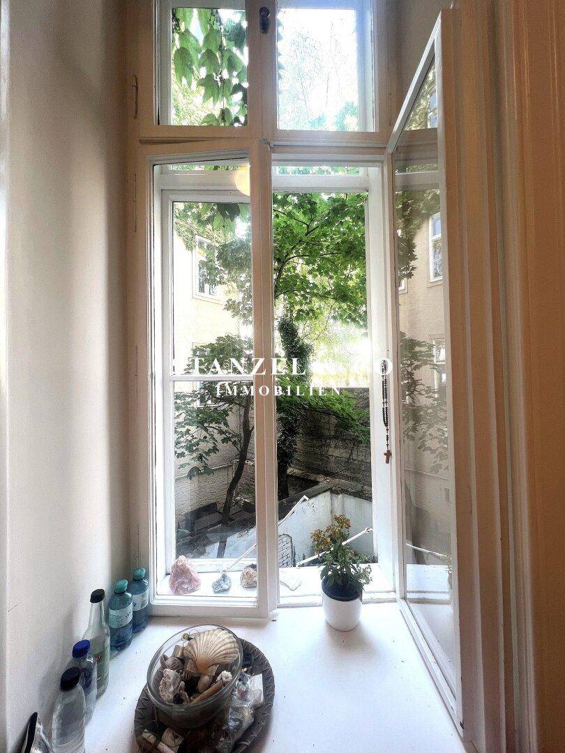 Fenster mit Blick auf den grünen Innenhof und die umliegenden Gebäude.