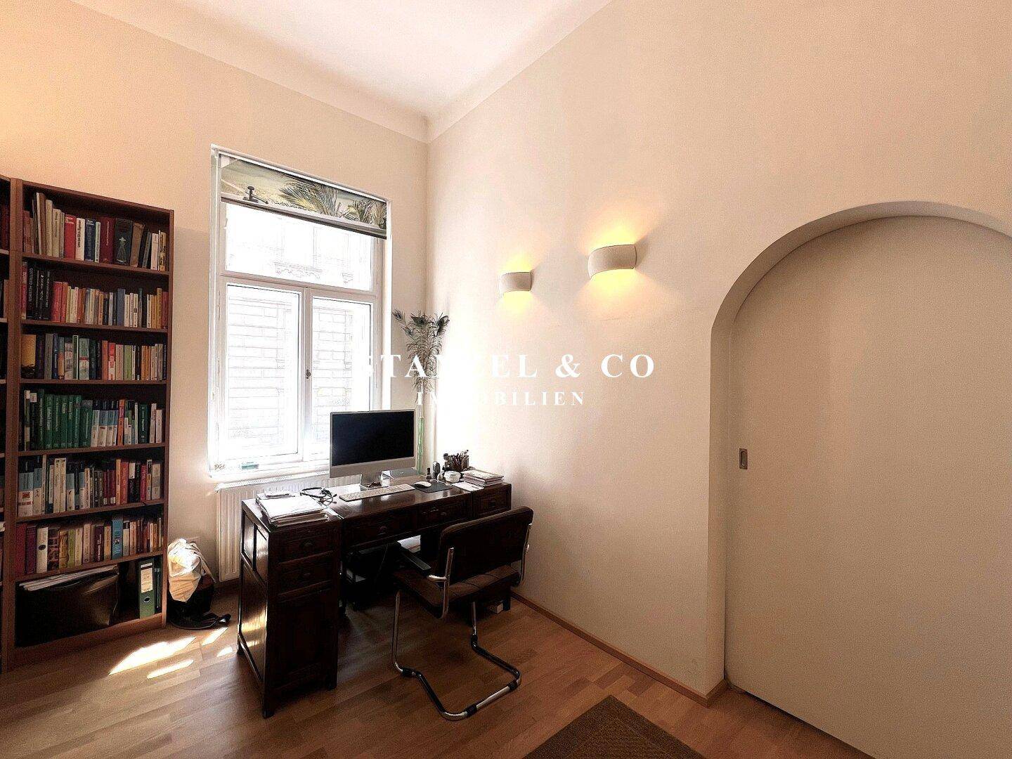 Helles Arbeitszimmer mit Schreibtisch, Bücherregal und Blick nach draußen.