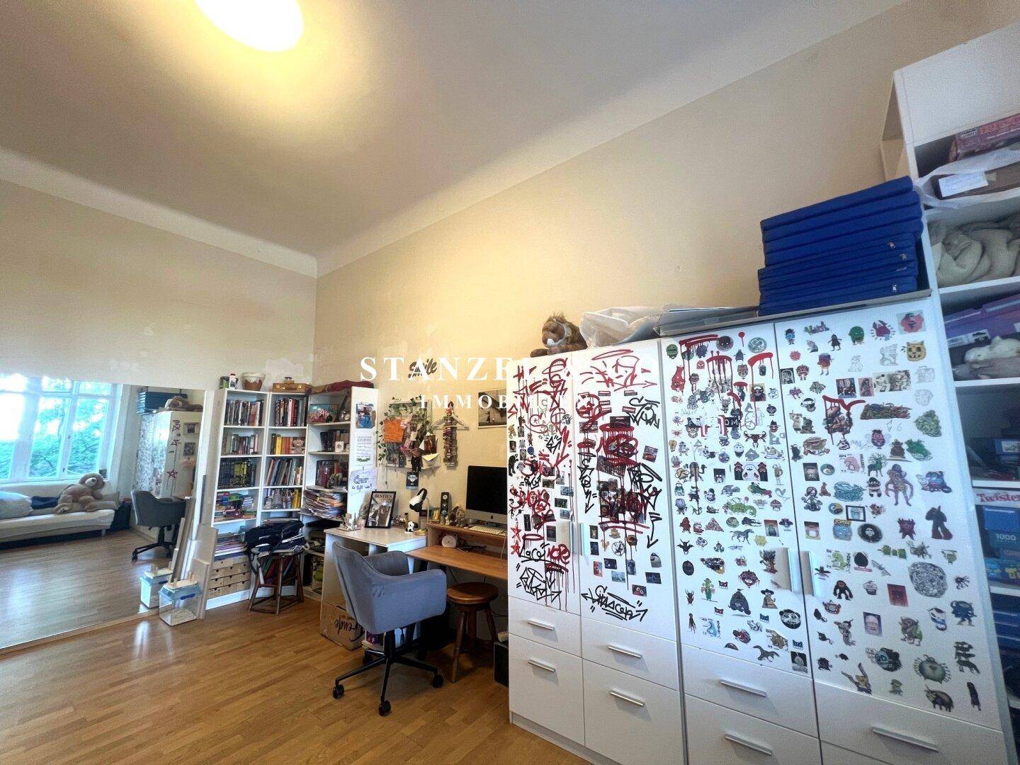 Geräumiges Zimmer mit hohen Decken, Holzfußboden und viel natürlichem Licht, perfekt zum Lernen und Entspannen.
