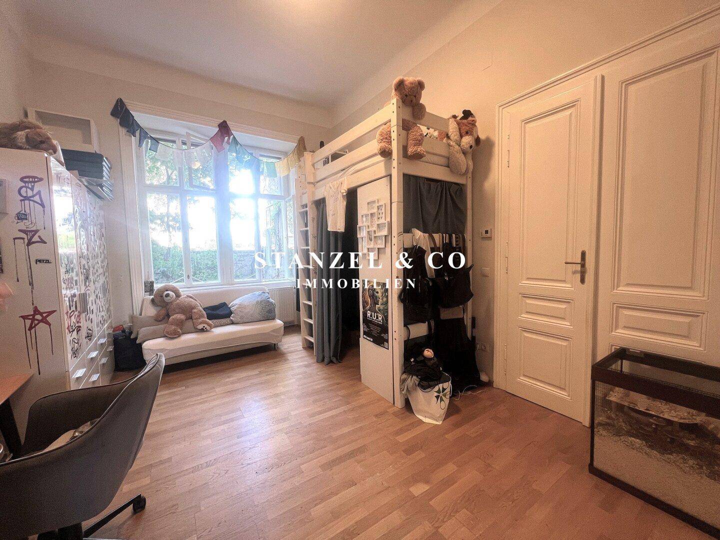 Kinderzimmer mit Hochbett, Schreibtisch und großem Fenster, das viel Licht hereinlässt, funktional eingerichtet.