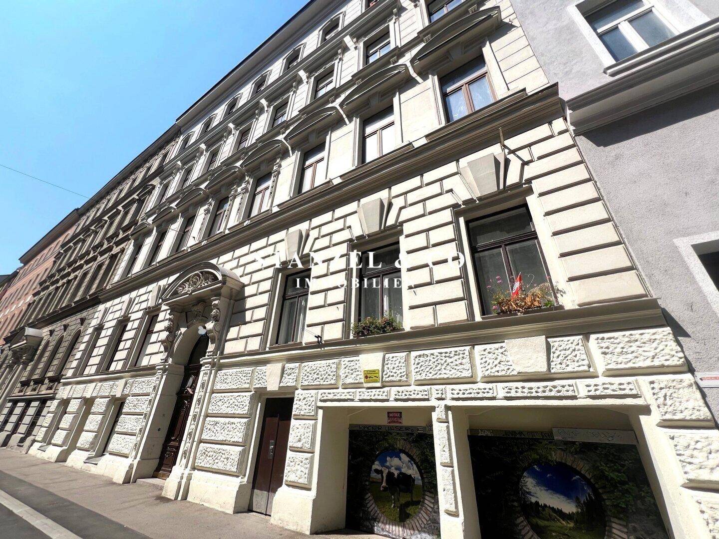 Historische Fassade eines Altbaus mit vielen Fenstern und architektonischen Details, beeindruckend und gepflegt.