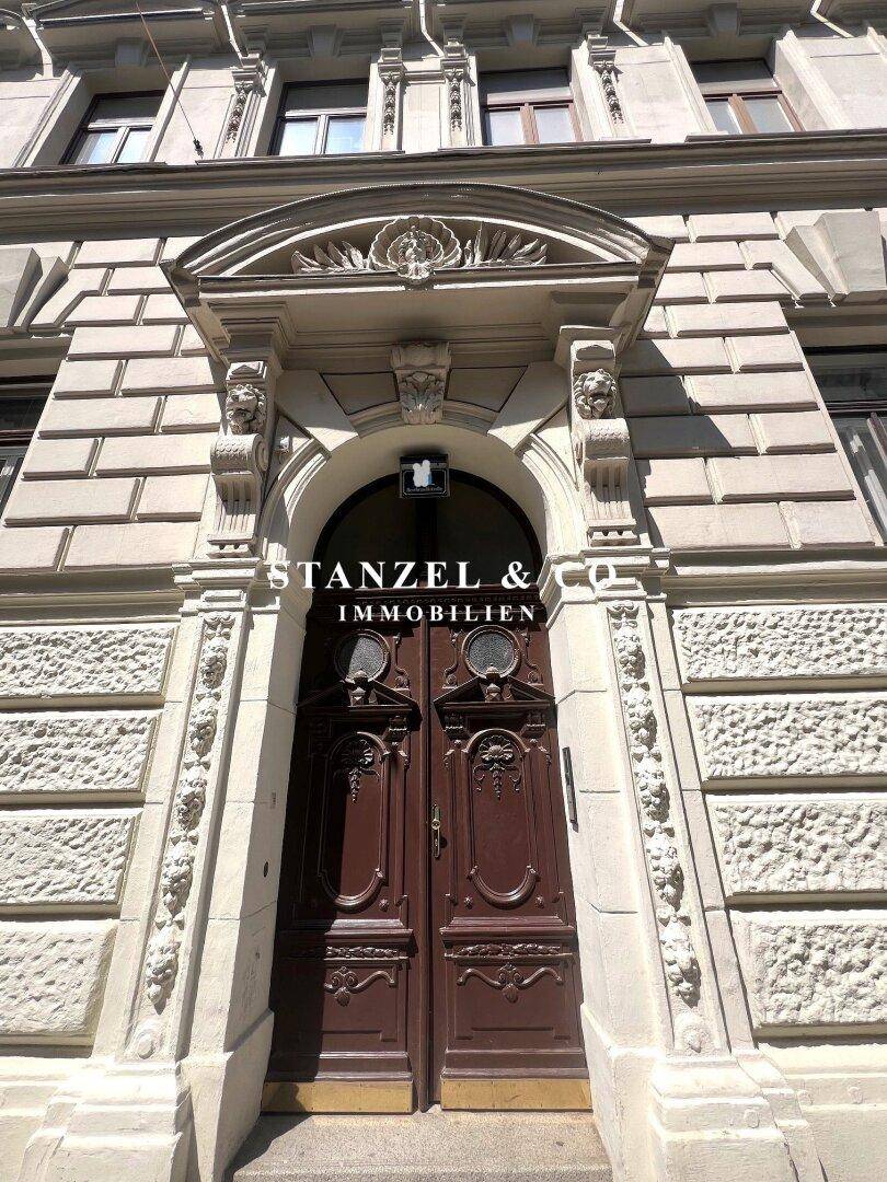 Elegantes Eingangsportal eines Altbaus mit kunstvollen Schnitzereien und doppelter Holztür, sehr repräsentativ.